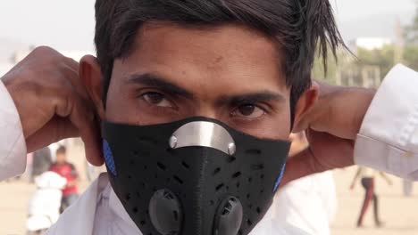 Indian-man-is-wearing-his-pollution-mask-and-turns-around-at-a-busy-Mela-festival-In-Rajasthan,-India