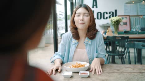 Beautiful-happy-Asian-women-lesbian-lgbt-couple-sitting-each-side-eating-a-plate-of-Italian-seafood-spaghetti-and-french-fries-at-restaurant-or-cafe-while-smiling-and-looking-at-food.