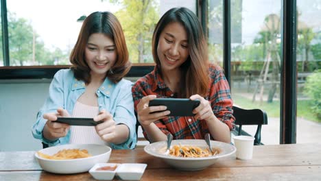 Glücklich-schöne-asiatische-Freunde-Frauen-Blogger-Smartphone-Fotos-und-Lebensmittel-Vlog-video-für-ihre-Abonnenten-und-ihrem-Kanal-im-Café.