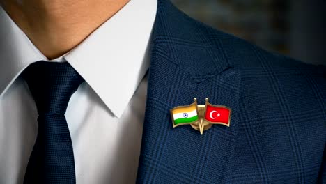Empresario-caminando-hacia-cámara-con-amigo-país-banderas-Pin-India---Turquía