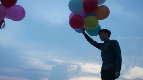 Young-couple-people-holding-balloon-with-sunset-background-in-slow-motion.