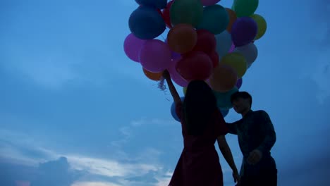 Young-couple-people-holding-balloon-with-sunset-background-in-slow-motion.