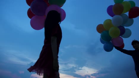 Young-couple-people-holding-balloon-with-sunset-background-in-slow-motion.