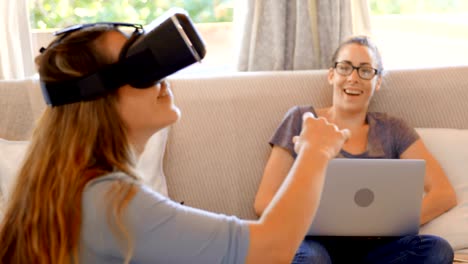 Lesbisches-Paar-mit-virtual-Reality-Kopfhörer-und-Laptop-im-Wohnzimmer-4k