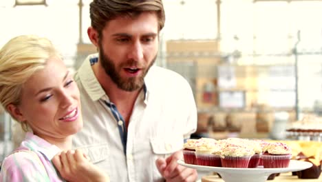 Pareja-feliz-apuntando-cupcakes-en-el-restaurante