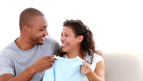 Cute-couple-on-the-sofa-holding-a-baby-clothes