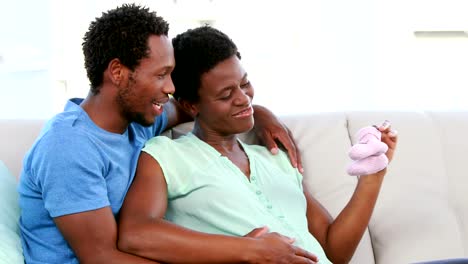 Pregnant-woman-showing-baby-shoes-on-the-sofa