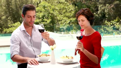 Smiling-couple-drinking-wine-poolside