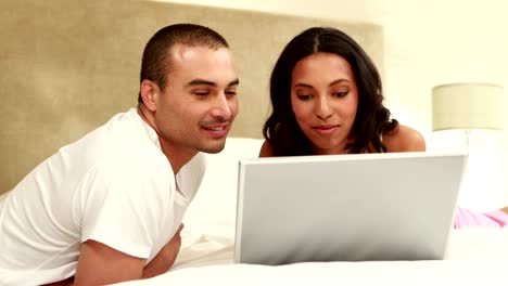 Relaxed-couple-using-laptop-on-bed