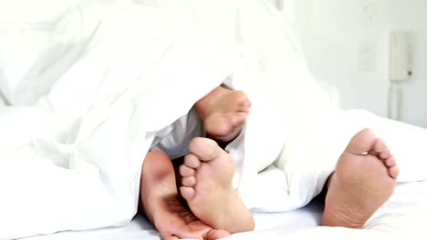 Young-couple-under-duvet-in-their-bed