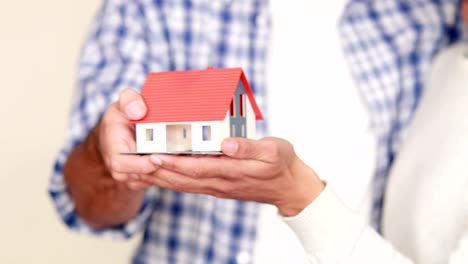 Homosexual-couple-holding-miniature-house-model