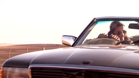 Young-adult-hipster-man-enjoys-driving-on-a-road-trip