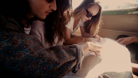 Group-of-young-hipster-friends-looking-at-map-in-vintage-van