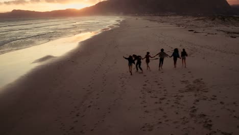 Junge-Freunde-genießen-einen-Spaziergang-am-Strand-bei-Sonnenuntergang