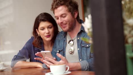 Mujer-y-hombre-sentado-en-la-cafetería-con-teléfono