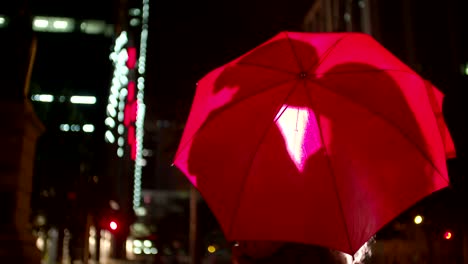 Couple-kissing-behind-a-red-umbrella-in-town