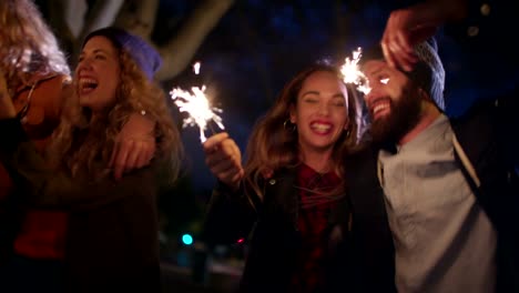 Teen-amigos-Hipster-celebra-conjuntamente-con-luces-de-Bengala-por-la-noche