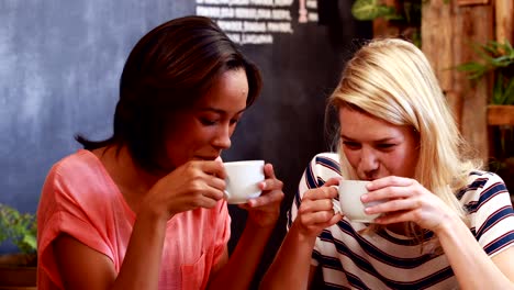 Amigos-bebiendo-café-y-observando-un-teléfono-inteligente