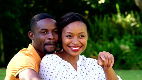 Cute-couple-sitting-on-the-grass-and-pointing-away