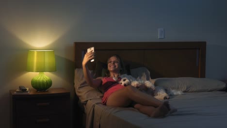 Frau-und-Hund-im-Bett-nehmen-Selfie-mit-Handy-in-der-Nacht