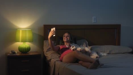 Mujer-y-perro-en-la-cama-tomando-Selfie-con-teléfono-en-la-noche