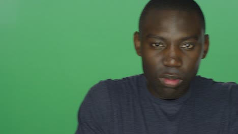 Young-African-American-man-glares,-on-a-green-screen-studio-background