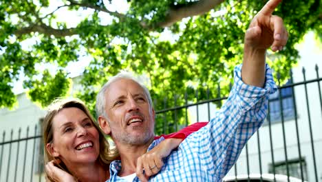 Portrait-of-mature-couple-is-embracing-and-pointing