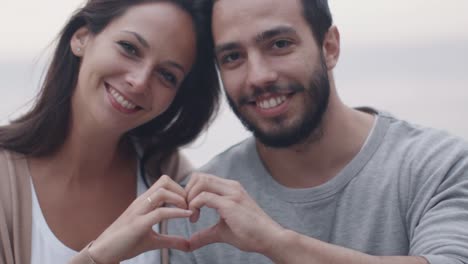 Happy-Smiling-Attractive-Couple-Forming-Hearth-Sign-with-their-Hands.