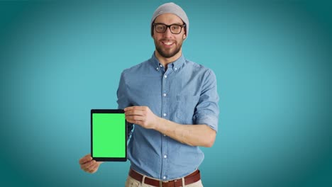 Mittelschuss-eines-schmelzenden-Moalen-Menschen,-der-sich-an-uns-Tablet-Computer-mit-isolierten-Mock-up-Green-Screen-vorstellt.-Schuss-auf-einen-Teal-Colored-Hintergrund.