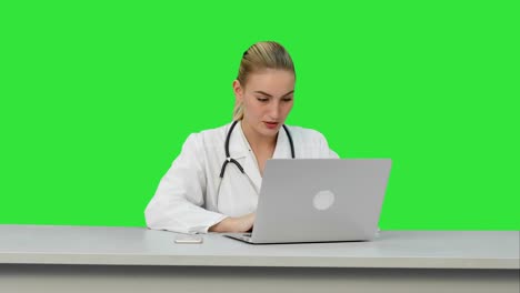 Seriouse-female-doctor-working-on-her-laptop-on-a-Green-Screen,-Chroma-Key