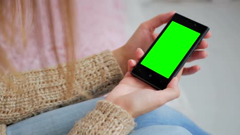 Woman-looking-at-smartphone-with-green-screen