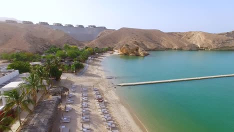 Vista-aérea-de-la-bahía-de-Muscat,-resort-de-buceo,-excursión-de-un-día-y-zona-de-relax,-de-cristalinas-aguas-del-océano-Índico,-la-playa-y-la-laguna-azul,-Omán,-Sultanato-de-la-Península-Arábiga,-4k-UHD