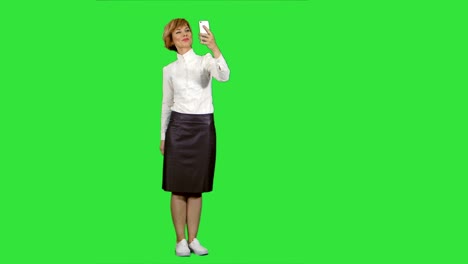 Mujer-Linda-sonriente-haciendo-foto-selfie-en-smartphone-en-una-pantalla-verde-Chroma-Key