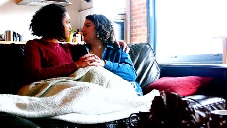 Lesbian-couple-holding-hands-while-sitting-on-a-couch