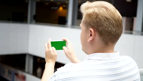Young-teenager-playing-game-on-smartphone-in-cafe.-Young-happy-man-playing-games-on-smartphone.-Smartphone-turns-on-on-white-background.-Easy-customizable-green-screen.-Computer-generated-image.