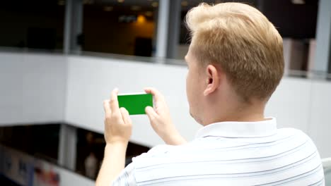 Junger-Teenager-Rollenspiel-auf-Smartphone-im-Café.-Glücklich-Jüngling-auf-Smartphone-zu-spielen.-Smartphone-schaltet-auf-weißem-Hintergrund.-Einfach-anpassbare-Greenscreen.-Computer-generierte-Bild.