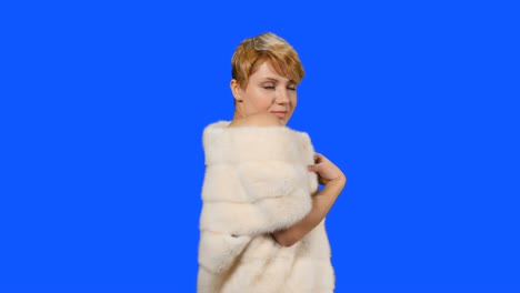 Beautiful-model-in-fur-cape-poses-for-camera-at-blue-background