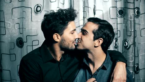 Smiling-gay-couple-exchanges-a-kiss-on-their-mouth