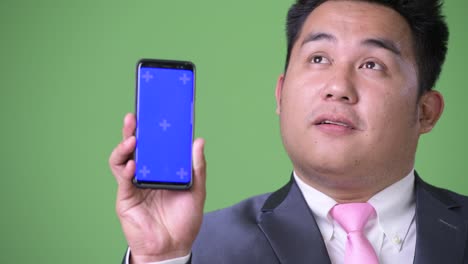 Young-handsome-overweight-Asian-businessman-against-green-background