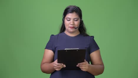 Young-overweight-beautiful-Indian-businesswoman-against-green-background