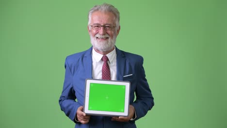 Handsome-senior-bearded-businessman-against-green-background