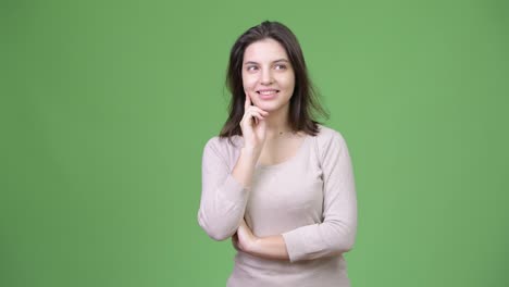 Young-happy-beautiful-woman-thinking-against-green-background