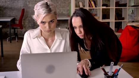 Young-businesswoman-flirting-with-her-female-worker-in-modern-office,-woman-annoyed-by-harassment-from-lesbian