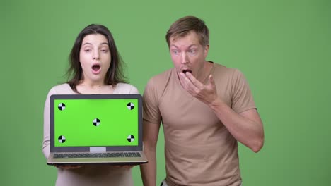 Young-couple-showing-laptop-while-looking-shocked-together