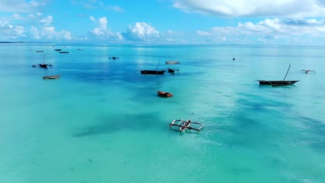 Aerial-view-of-a-fisherman-sails-on-a-wooden-boat-on-clear-blue-water-along-a-tropical-exotic-beach-in-Africa