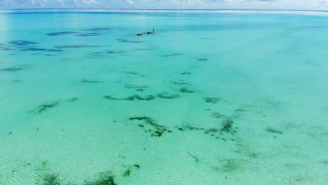 Aerial-view-of-a-fisherman-sails-on-a-wooden-boat-on-clear-blue-water-along-a-tropical-exotic-beach-in-Africa