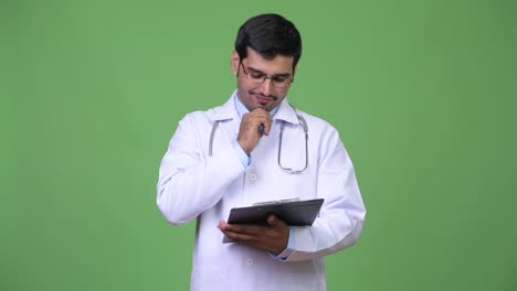 Young-handsome-Persian-man-doctor-reading-on-clipboard