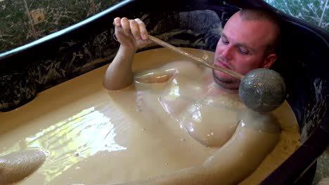 Man-lies-in-the-mud-bath-and-pours-from-the-ladle