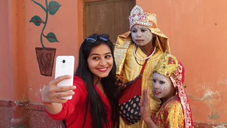 Handheld-shot-of-an-urban-Indian-female-tourists-with-two-females-dressed-as-goddess-taking-selfie-photography-making-video