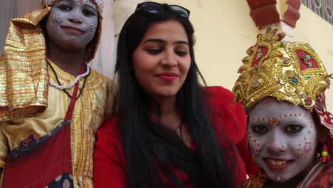 POV-of-a-camera-taking-selfies-of-a-urban-tourist-posing-with-two-child-actors-in-goddess-make-up-with-a-smart-mobile-phone-camera-handheld